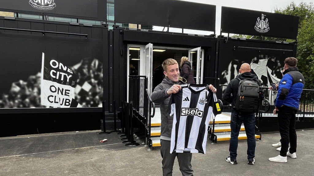 Newcastle Fan Holding Up New Shirt Outside Store